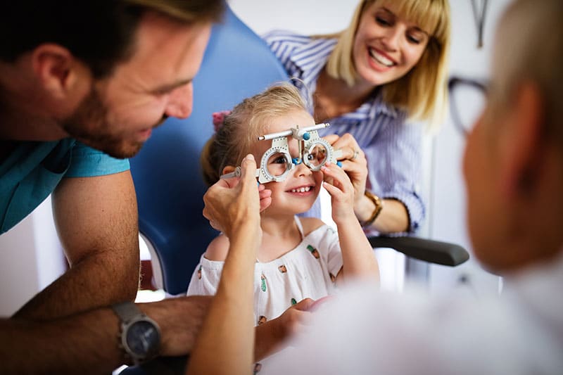 little girl smiling as she gets an eye exam